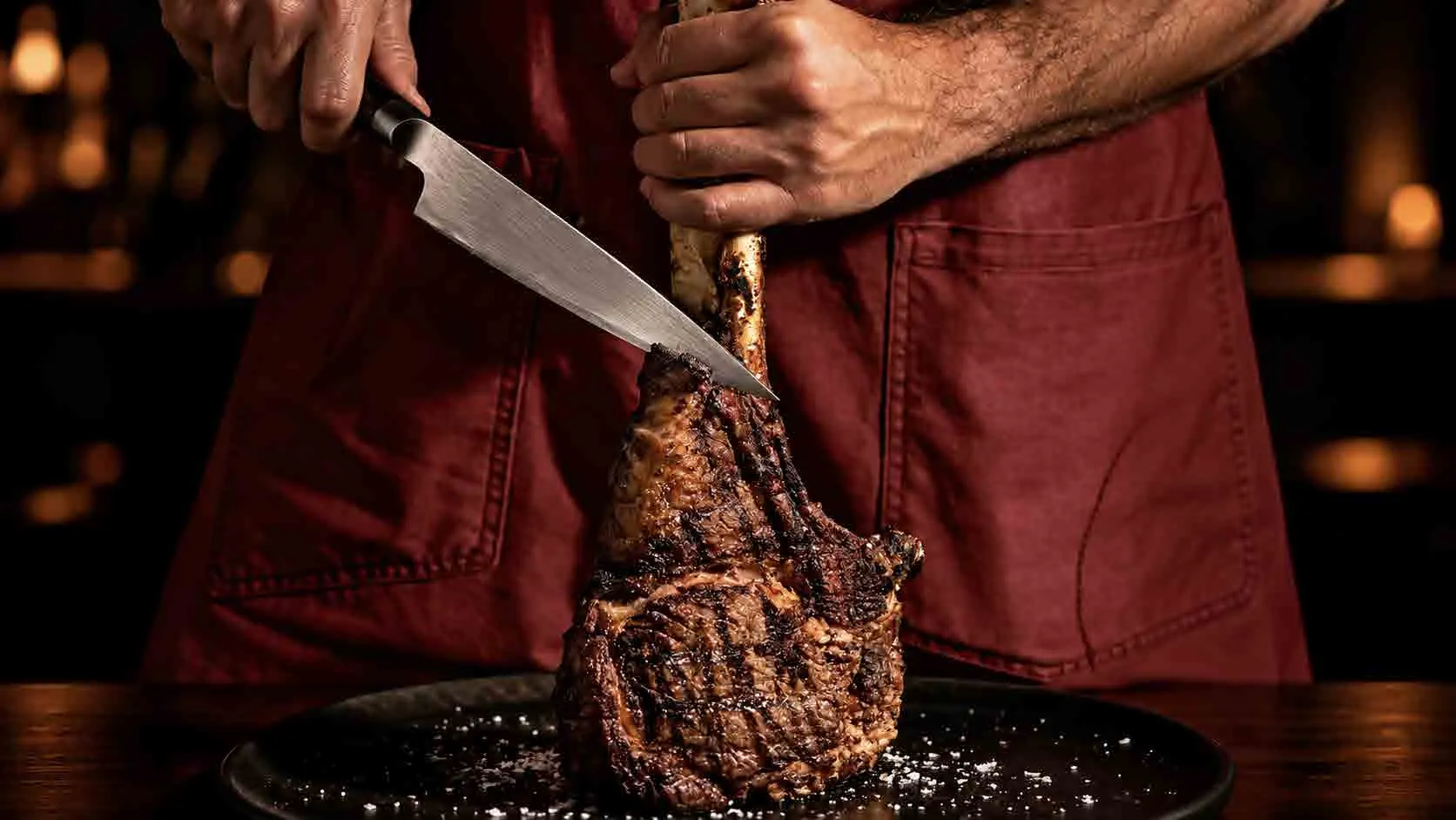 Chef fatiando um tomahawk grelhado sobre a tábua